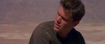 Movie still from “Gerry” (2002), directed by Gus Van Sant – A person wearing a black t - shirt; Close Up shot, Over the shoulder angle