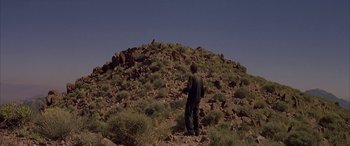Movie still from “Gerry” (2002), directed by Gus Van Sant – A man standing on top of a hill looking at the sky; Extreme Wide shot, Low angle