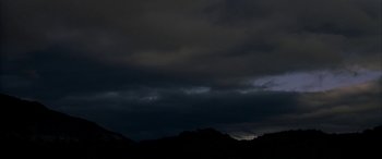 Movie still from “Gerry” (2002), directed by Gus Van Sant – A dark cloudy sky over a mountainous area; Extreme Wide shot, Low angle