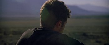 Movie still from “Gerry” (2002), directed by Gus Van Sant – A young man is looking out over a field at dusk; Close Up shot, Over the shoulder angle