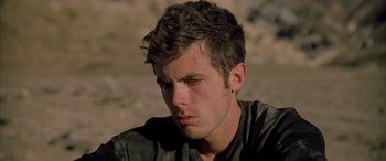 Movie still from “Gerry” (2002), directed by Gus Van Sant – A young man with a serious look on his face; Close Up shot, Low angle