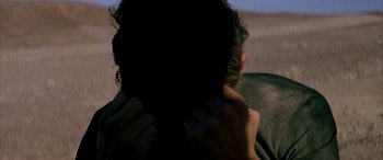 Movie still from “Gerry” (2002), directed by Gus Van Sant – A person with their hands on their shoulders; Close Up shot, Over the shoulder angle
