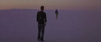 Movie still from “Gerry” (2002), directed by Gus Van Sant – A man standing in the middle of the desert; Wide shot, Over the shoulder angle