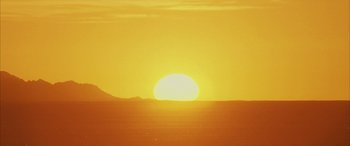 Movie still from “Gerry” (2002), directed by Gus Van Sant – The sun is setting over a large body of water; Extreme Wide shot, Low angle