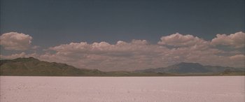 Movie still from “Gerry” (2002), directed by Gus Van Sant – A large expanse of land with a mountain range in the background; Extreme Wide shot, Low angle