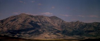 Movie still from “Gerry” (2002), directed by Gus Van Sant – A large mountain range with a sky background; Extreme Wide shot, Low angle