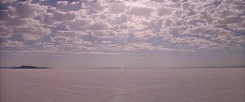 Movie still from “Gerry” (2002), directed by Gus Van Sant – A view of a vast expanse of snow and a cloudy sky; Extreme Wide shot, Low angle