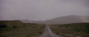 Movie still from “Gerry” (2002), directed by Gus Van Sant – A dirt road that is in the middle of a field; Extreme Wide shot, High angle