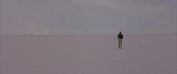Movie still from “Gerry” (2002), directed by Gus Van Sant – A man standing on top of a snow covered slope; Extreme Wide shot, High angle