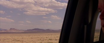 Movie still from “Gerry” (2002), directed by Gus Van Sant – A view from a car window of a desert landscape; Extreme Wide shot, Over the shoulder angle