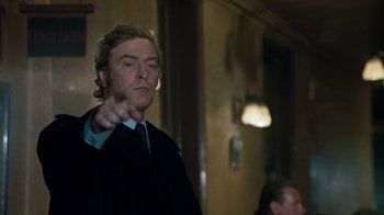 Movie still from “Get Carter” (1971), directed by Mike Hodges – A man in a suit and tie pointing at something; Medium shot, Low angle