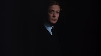 Movie still from “Get Carter” (1971), directed by Mike Hodges – A man wearing a suit and tie standing in the dark; Close Up shot, Low angle