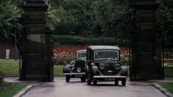 Movie still from “Get Carter” (1971), directed by Mike Hodges – Two old cars parked in front of a building; Extreme Wide shot, High angle