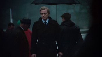 Movie still from “Get Carter” (1971), directed by Mike Hodges – A man in a suit and tie holding an umbrella; Medium shot, Low angle