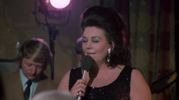 Movie still from “Get Carter” (1971), directed by Mike Hodges – A woman in a black dress is holding a microphone; Close Up shot, Over the shoulder angle