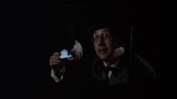 Movie still from “Get Carter” (1971), directed by Mike Hodges – A man in a hat and glasses holding a card; Close Up shot, Over the shoulder angle