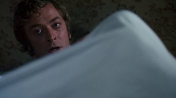 Movie still from “Get Carter” (1971), directed by Mike Hodges – A man is hiding under a blanket in a bed; Close Up shot, Over the shoulder angle