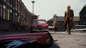 Movie still from “Get Carter” (1971), directed by Mike Hodges – A man walking down a street near a red car; Extreme Wide shot, Low angle