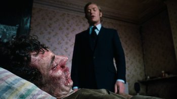 Movie still from “Get Carter” (1971), directed by Mike Hodges – A man standing next to a dead body in a room; Close Up shot, Low angle