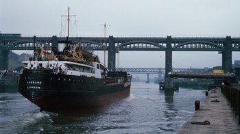 Movie still from “Get Carter” (1971), directed by Mike Hodges – A large boat in a body of water near a bridge; Extreme Wide shot, Low angle