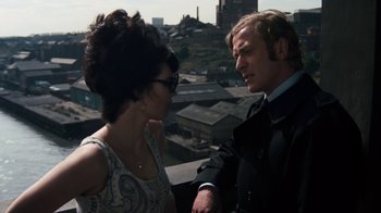 Movie still from “Get Carter” (1971), directed by Mike Hodges – A man and a woman are standing on a balcony; Medium shot, Over the shoulder angle