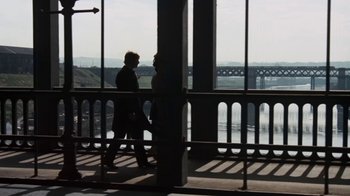 Movie still from “Get Carter” (1971), directed by Mike Hodges – Two people are walking on a balcony near a bridge; Wide shot, Low angle