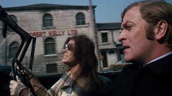 Movie still from “Get Carter” (1971), directed by Mike Hodges – A man and a woman riding in the back of a car; Medium shot, Low angle