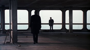 Movie still from “Get Carter” (1971), directed by Mike Hodges – Two men standing in an empty parking garage; Wide shot, Low angle