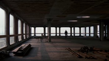 Movie still from “Get Carter” (1971), directed by Mike Hodges – A man standing in a room with a view of the ocean; Extreme Wide shot, Low angle