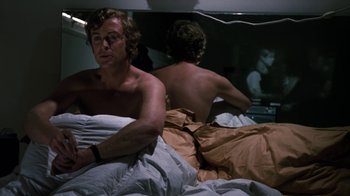 Movie still from “Get Carter” (1971), directed by Mike Hodges – A man sitting on a bed next to another man; Medium shot, Low angle