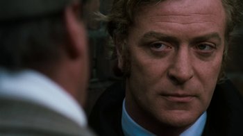 Movie still from “Get Carter” (1971), directed by Mike Hodges – A man's face as he stares at the camera; Close Up shot, Over the shoulder angle