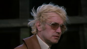 Movie still from “Get Carter” (1971), directed by Mike Hodges – A person wearing a suit and sunglasses; Close Up shot, Low angle