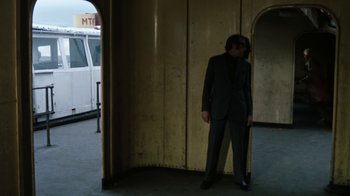 Movie still from “Get Carter” (1971), directed by Mike Hodges – A man in a suit standing in front of a bus; Wide shot, Low angle