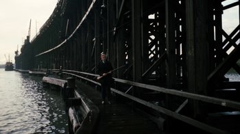 Movie still from “Get Carter” (1971), directed by Mike Hodges – A man standing on a dock holding a fishing rod; Extreme Wide shot, High angle