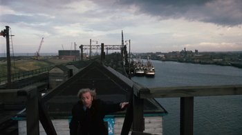 Movie still from “Get Carter” (1971), directed by Mike Hodges – A woman standing on a deck overlooking a river; Extreme Wide shot, High angle