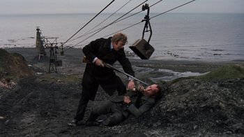 Movie still from “Get Carter” (1971), directed by Mike Hodges – Two men in business attire are fighting over a man on the ground; Wide shot, High angle