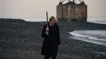Movie still from “Get Carter” (1971), directed by Mike Hodges – A man in a black coat holding an umbrella; Medium shot, Low angle