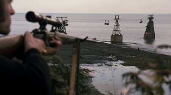 Movie still from “Get Carter” (1971), directed by Mike Hodges – A man looking through a telescope at the ocean; Extreme Wide shot, High angle