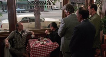 Movie still from “Get Shorty” (1995), directed by Barry Sonnenfeld – A group of men sitting at a table with a cup of coffee; Wide shot, Over the shoulder angle