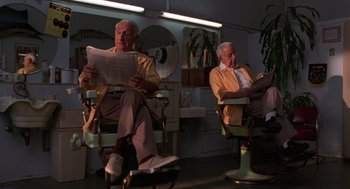 Movie still from “Get Shorty” (1995), directed by Barry Sonnenfeld – Two older men sitting in barber chairs reading newspapers; Medium shot, Low angle