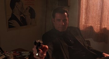 Movie still from “Get Shorty” (1995), directed by Barry Sonnenfeld – A man in a suit holding a gun in his hand; Medium shot, Low angle