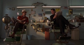 Movie still from “Get Shorty” (1995), directed by Barry Sonnenfeld – Two men sitting in barber chairs in front of a mirror; Medium shot, Low angle