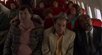 Movie still from “Get Shorty” (1995), directed by Barry Sonnenfeld – A man with a hat sitting next to another man on a plane; Medium shot, High angle