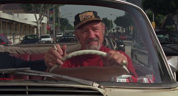 Movie still from “Get Shorty” (1995), directed by Barry Sonnenfeld – An older man driving a car in the middle of the street; Medium shot, Low angle