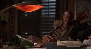 Movie still from “Get Shorty” (1995), directed by Barry Sonnenfeld – An older man sitting at a table with a phone; Medium shot, High angle