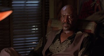 Movie still from “Get Shorty” (1995), directed by Barry Sonnenfeld – An older man sitting in a chair in a room; Close Up shot, Low angle