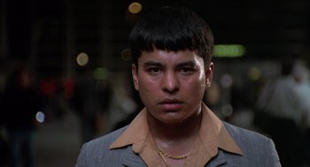 Movie still from “Get Shorty” (1995), directed by Barry Sonnenfeld – A young man with short black hair wearing a suit; Close Up shot, Low angle