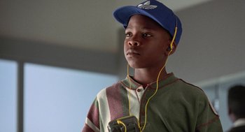 Movie still from “Get Shorty” (1995), directed by Barry Sonnenfeld – A young boy wearing a blue hat and holding a cell phone; Close Up shot, Low angle