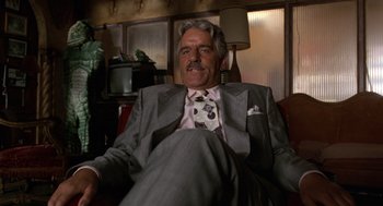 Movie still from “Get Shorty” (1995), directed by Barry Sonnenfeld – An older man sitting in a chair wearing a suit and tie; Medium shot, Low angle