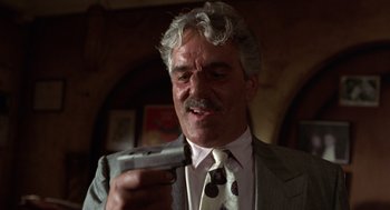 Movie still from “Get Shorty” (1995), directed by Barry Sonnenfeld – An older man in a suit and tie looking at a camera; Close Up shot, Low angle